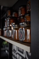Glass jars filled with bright red pepper sauce lined up on a kitchen counter.