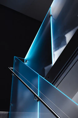 A sleek modern steel staircase with glass panels in a bright, minimalist interior.