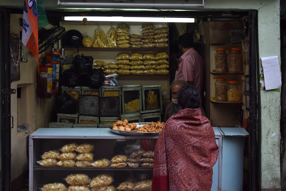 a woman standing in front of a store filled with food