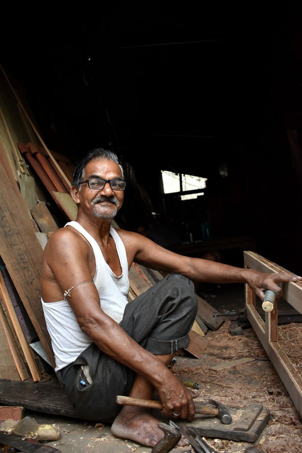 un uomo seduto a terra che lavora su un pezzo di legno