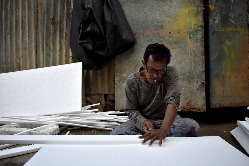 a man sitting on the ground working on a piece of paper
