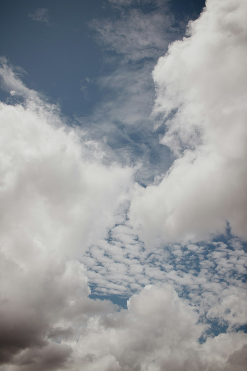 a plane flying through a cloudy blue sky