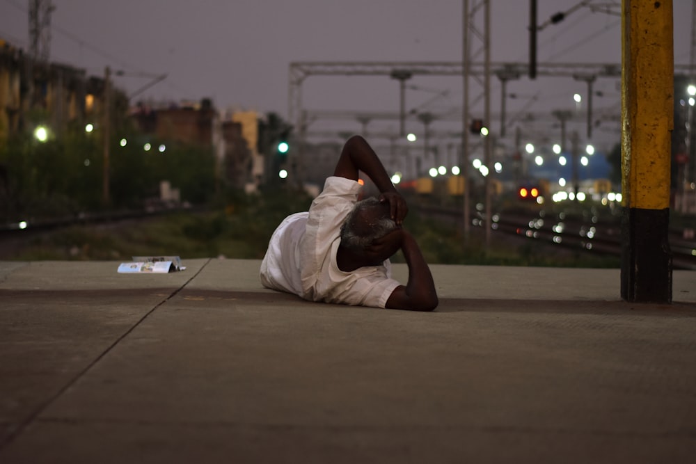 a man laying on the ground next to a train track