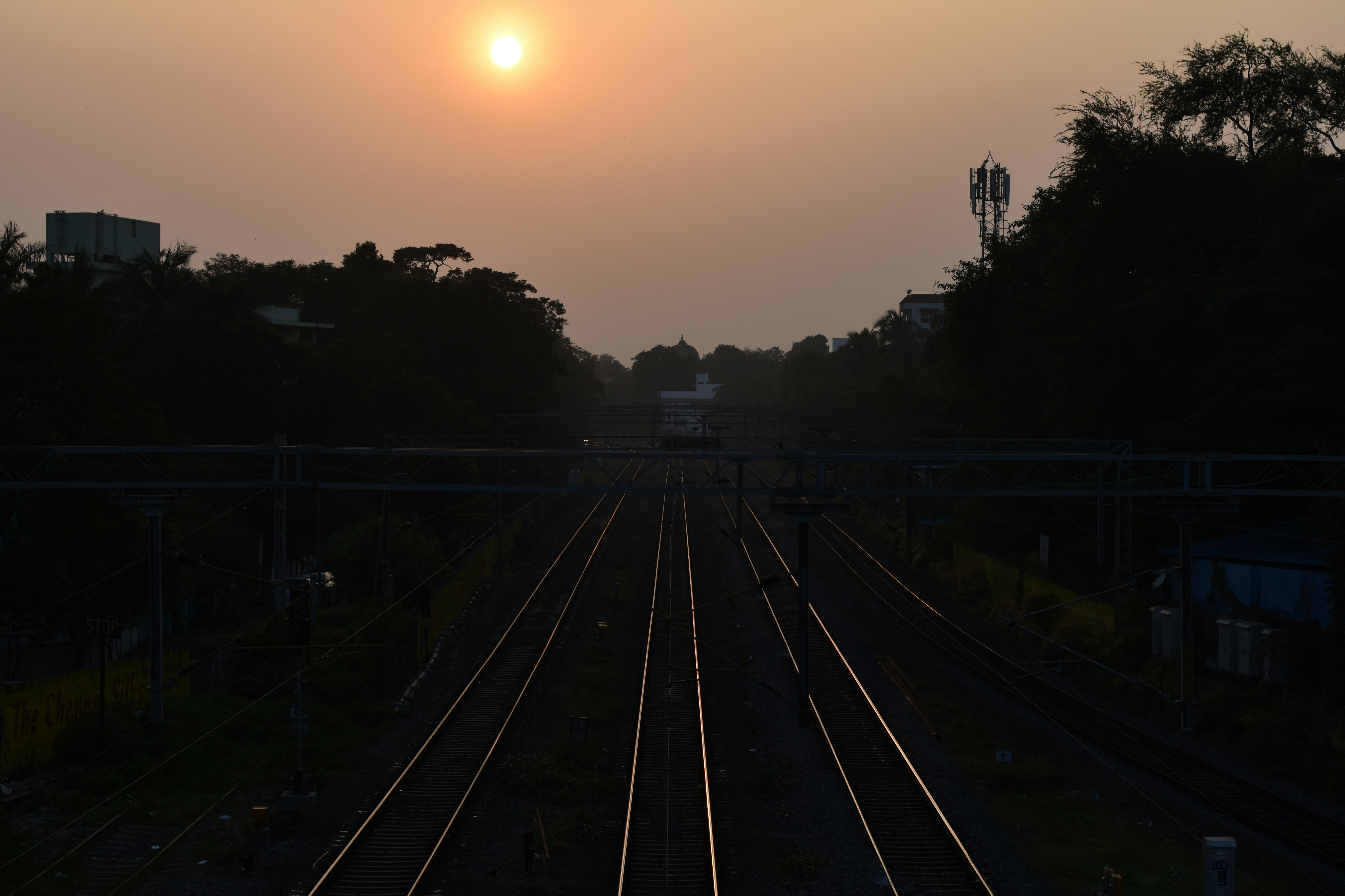 An aerial shot of a modern, well-maintained Indian Railways train pulling into a newly renovated station at sunset.