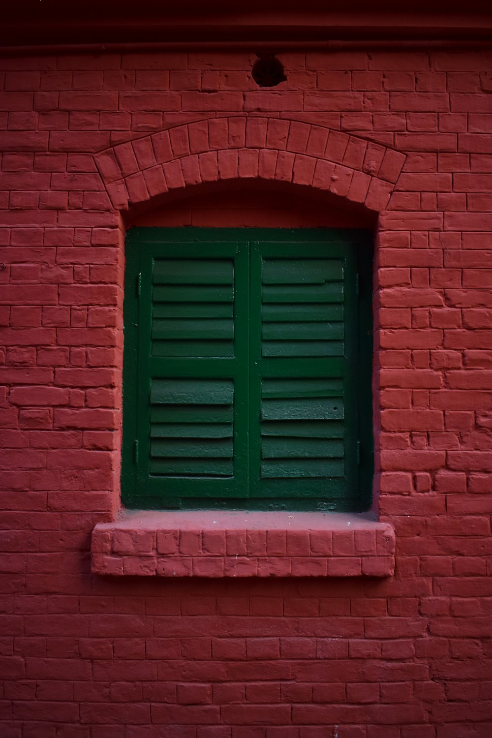 a red brick building with a green window