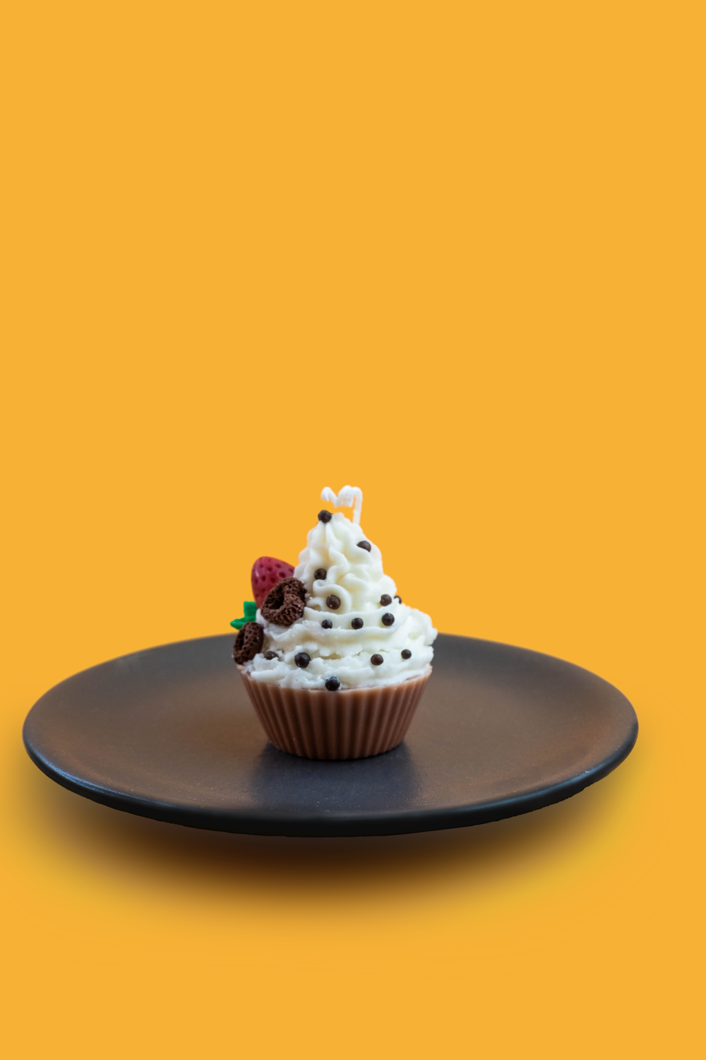 a cupcake with white frosting and sprinkles on a black plate