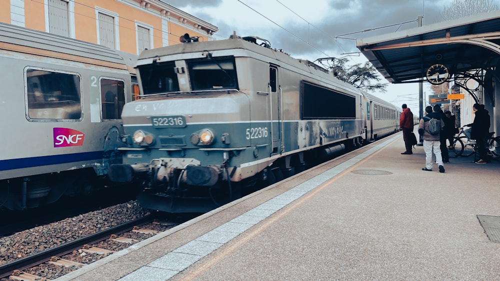 um trem prateado puxando para uma estação de trem