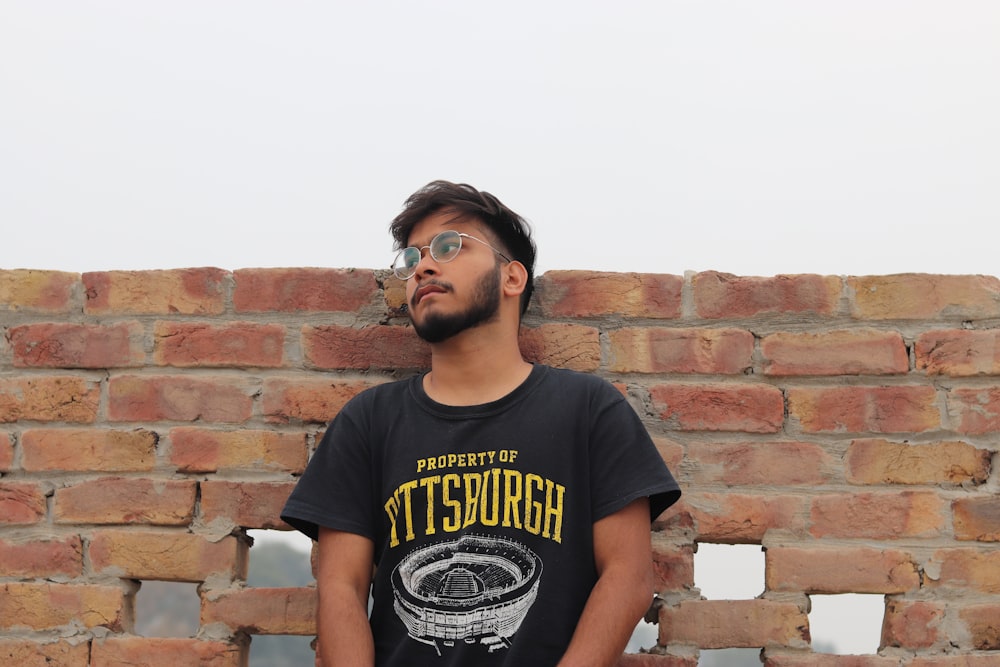 a man standing in front of a brick wall