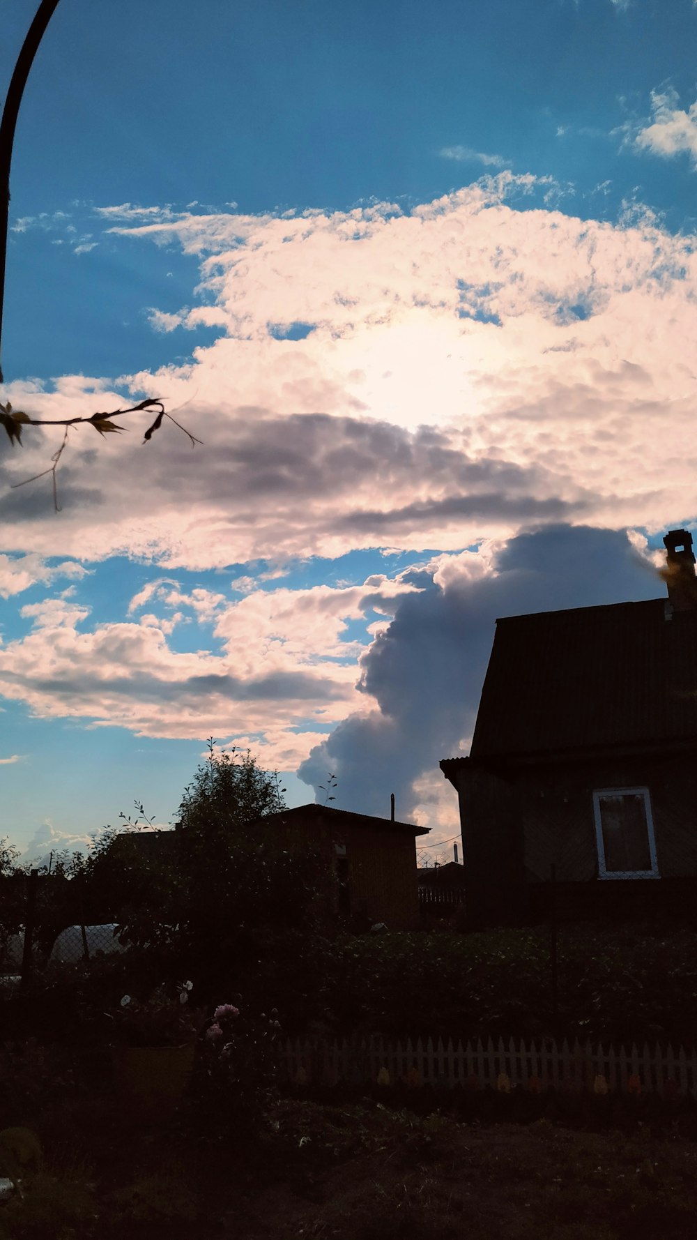 Une maison et un lampadaire devant un ciel nuageux
