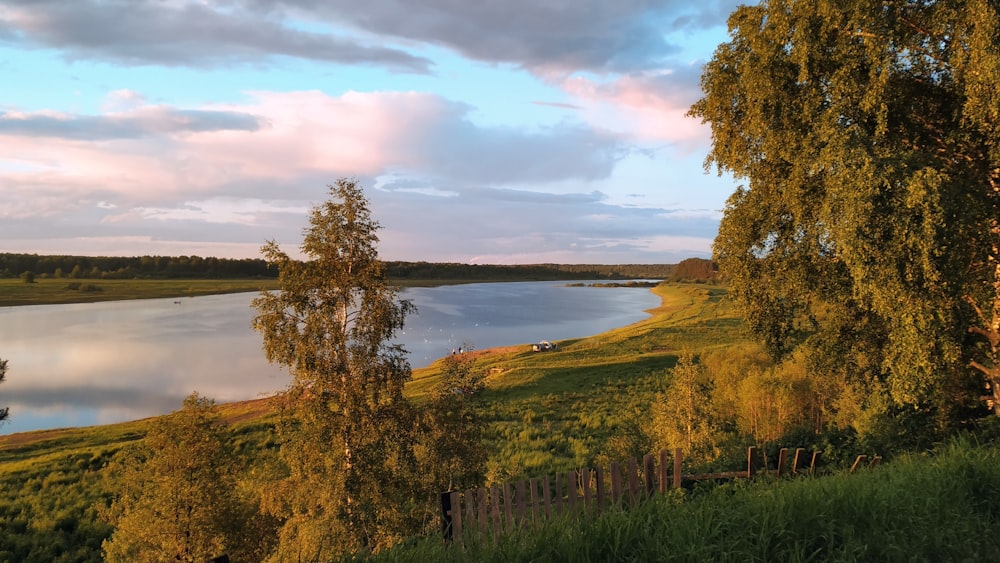 a large body of water surrounded by a lush green field