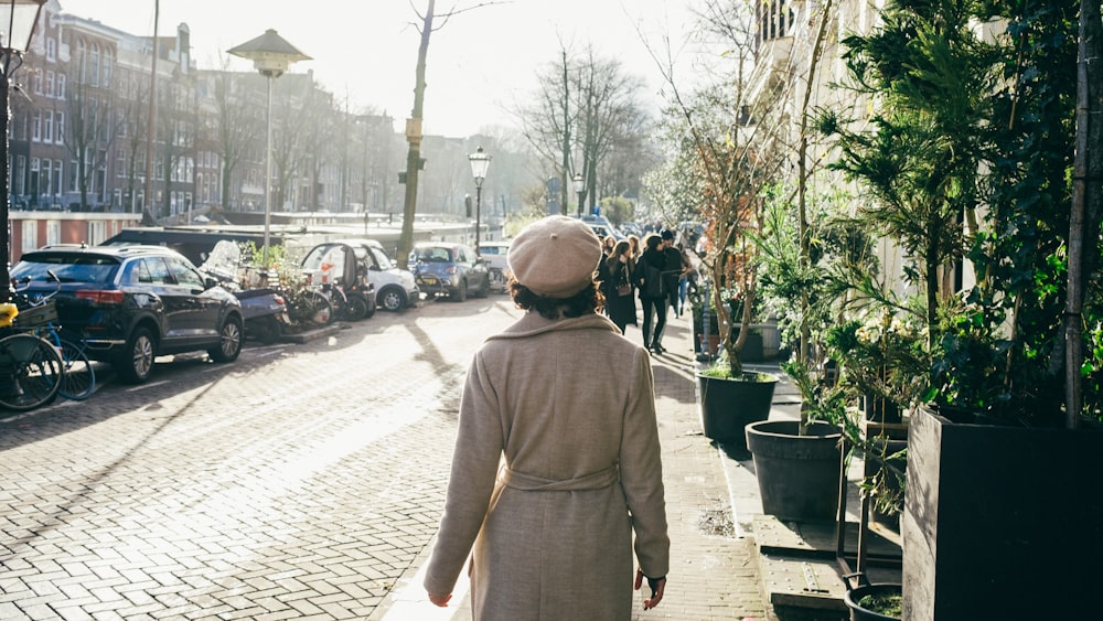 a woman walking down a street next to parked cars