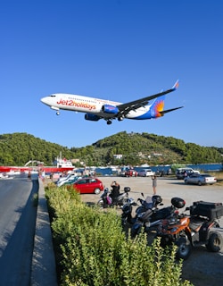 a large jetliner flying over a lush green hillside