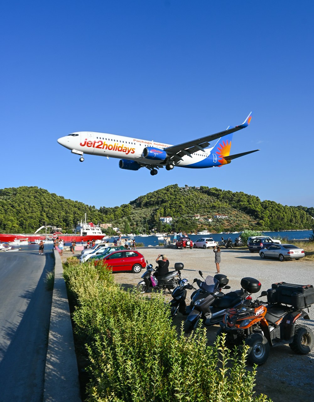 a large jetliner flying over a lush green hillside