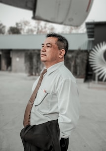 a man in a dress shirt and tie standing in front of a building