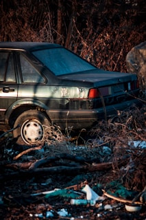 A junk car that is parked in the grass.