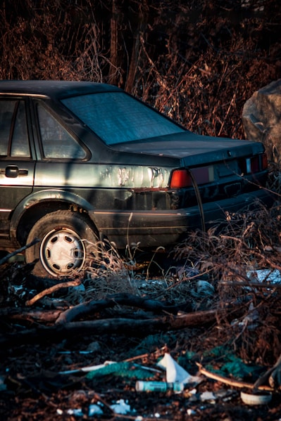 A junk car that is parked in the grass.