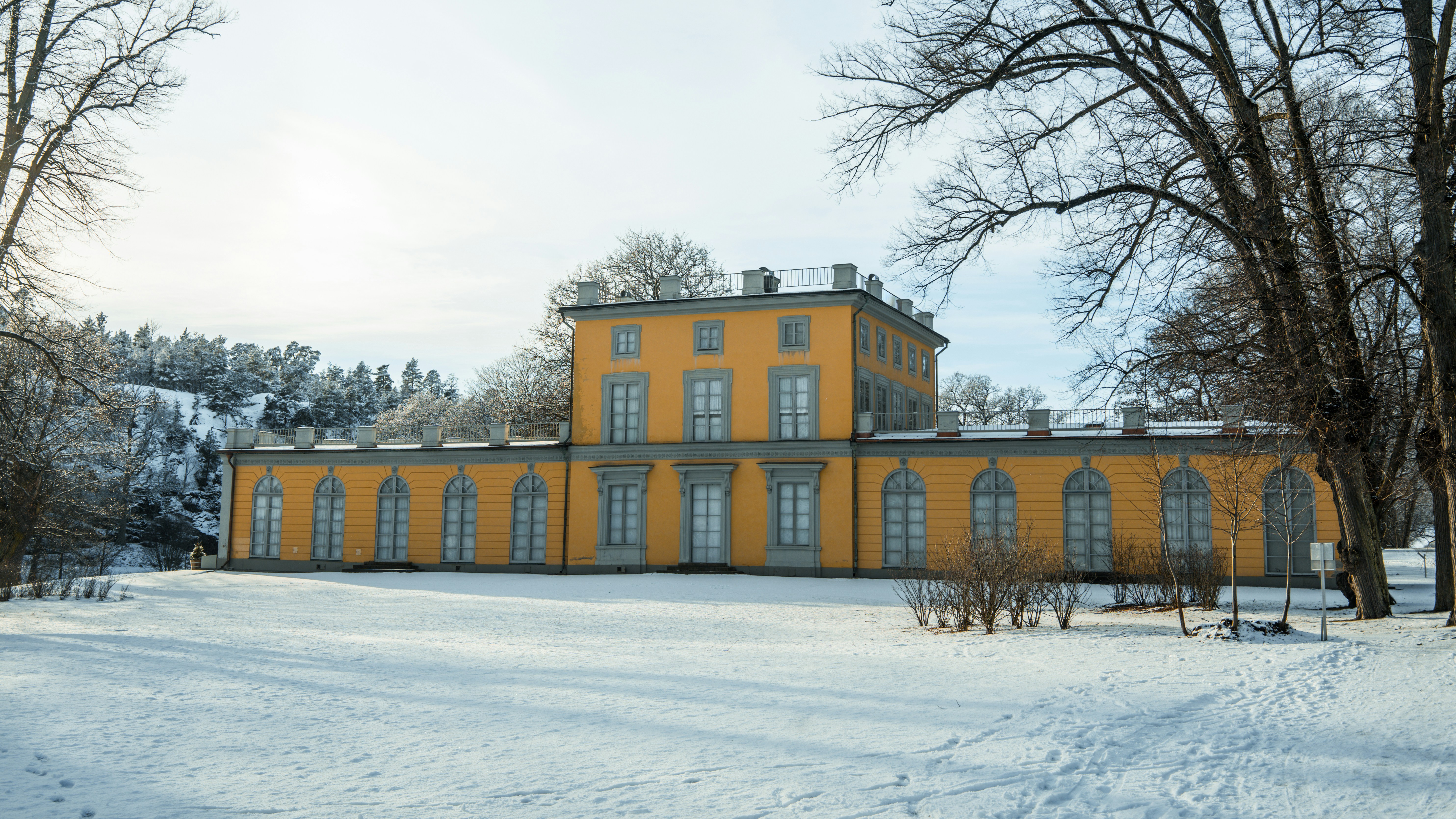 a large yellow building in the middle of a snowy field, Frontside of the kings summer palace (during winter) in Stockholm 2