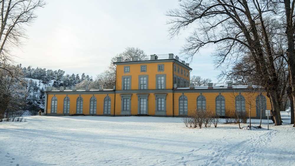 a large yellow building in the middle of a snowy field