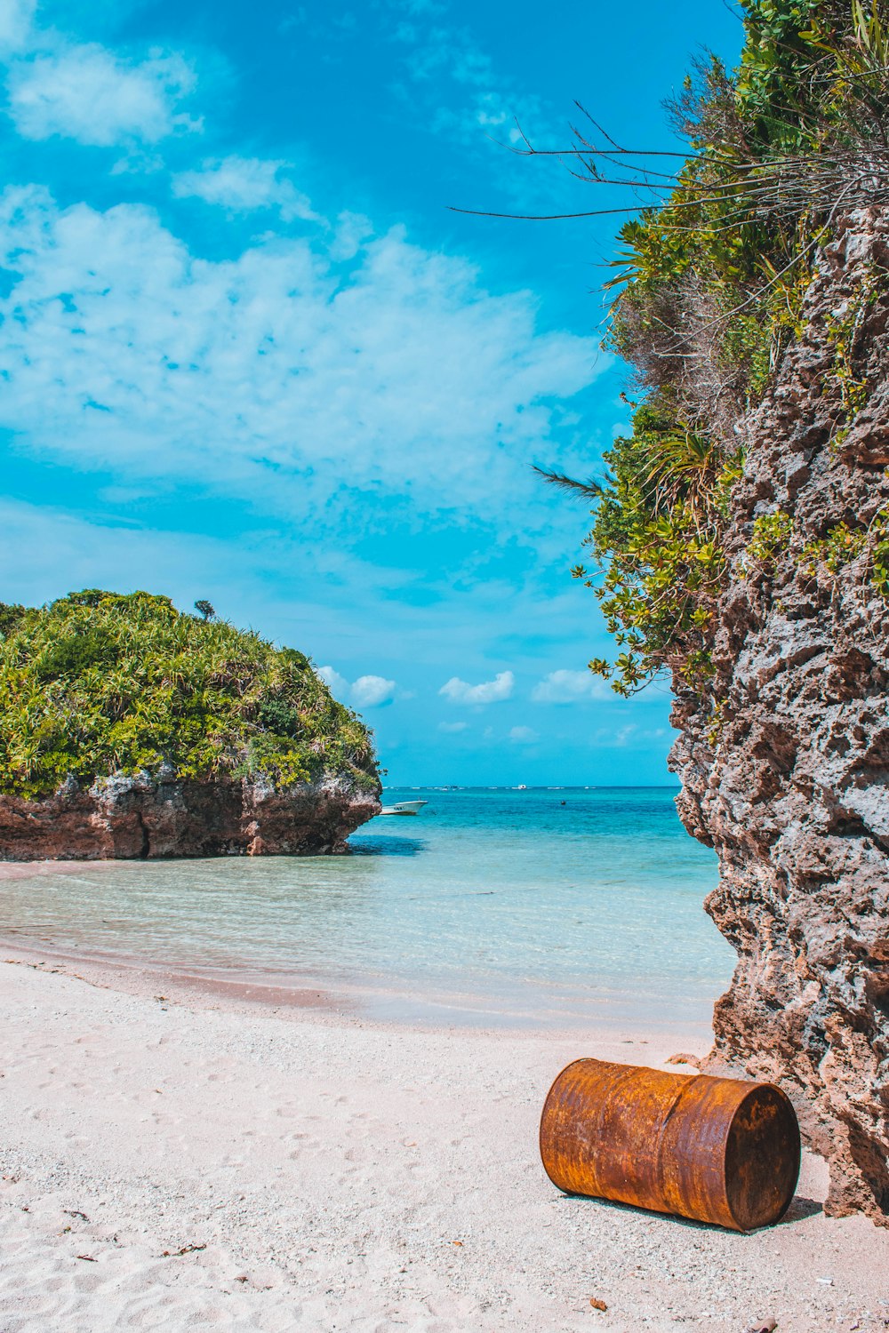 a barrel laying on a beach next to a cliff