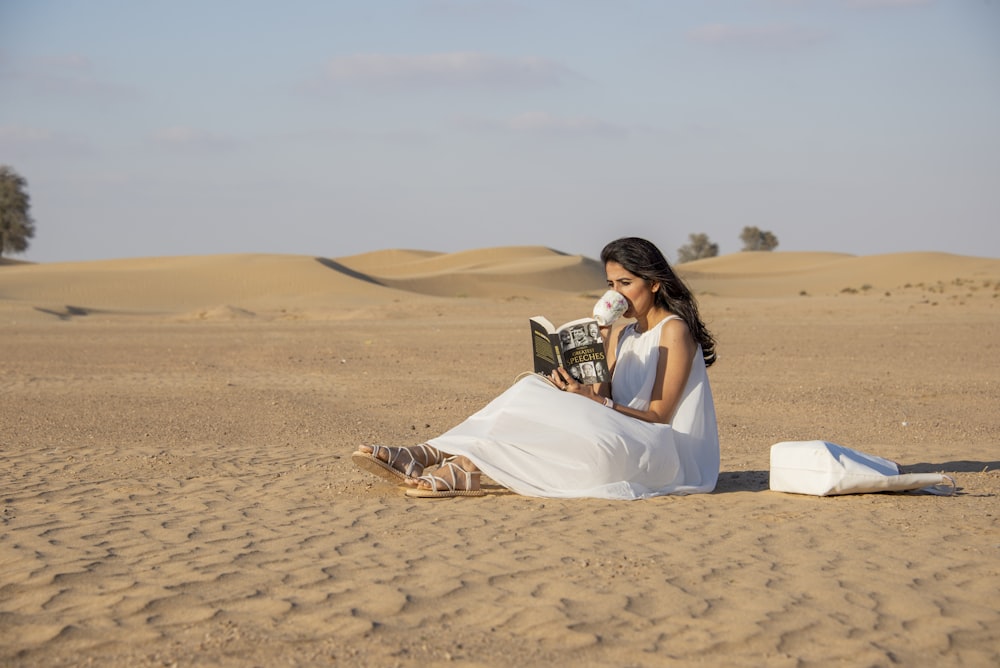 a woman sitting in the desert reading a book