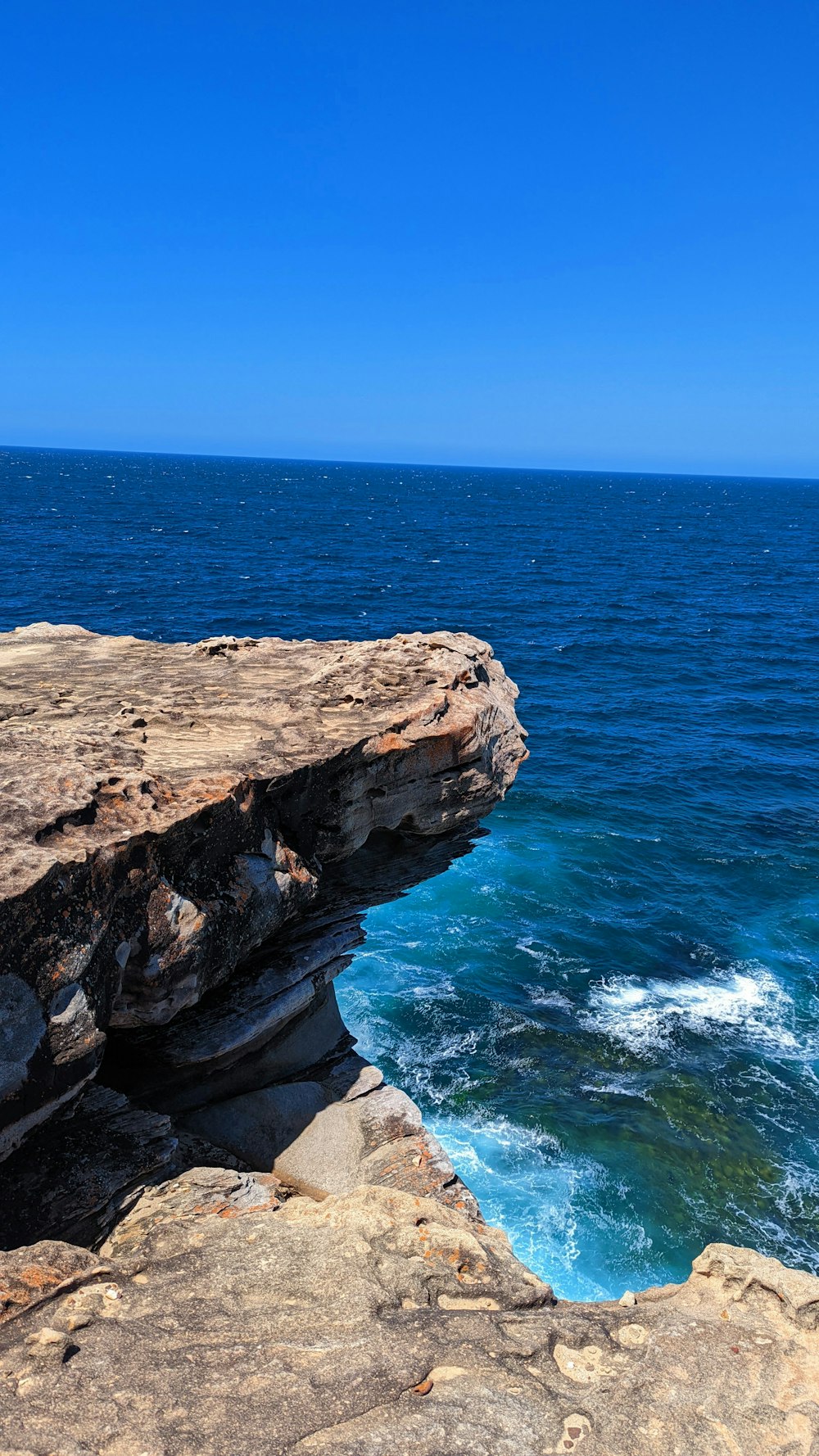 a person sitting on a cliff overlooking the ocean