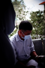 a man wearing a face mask sitting on a bench