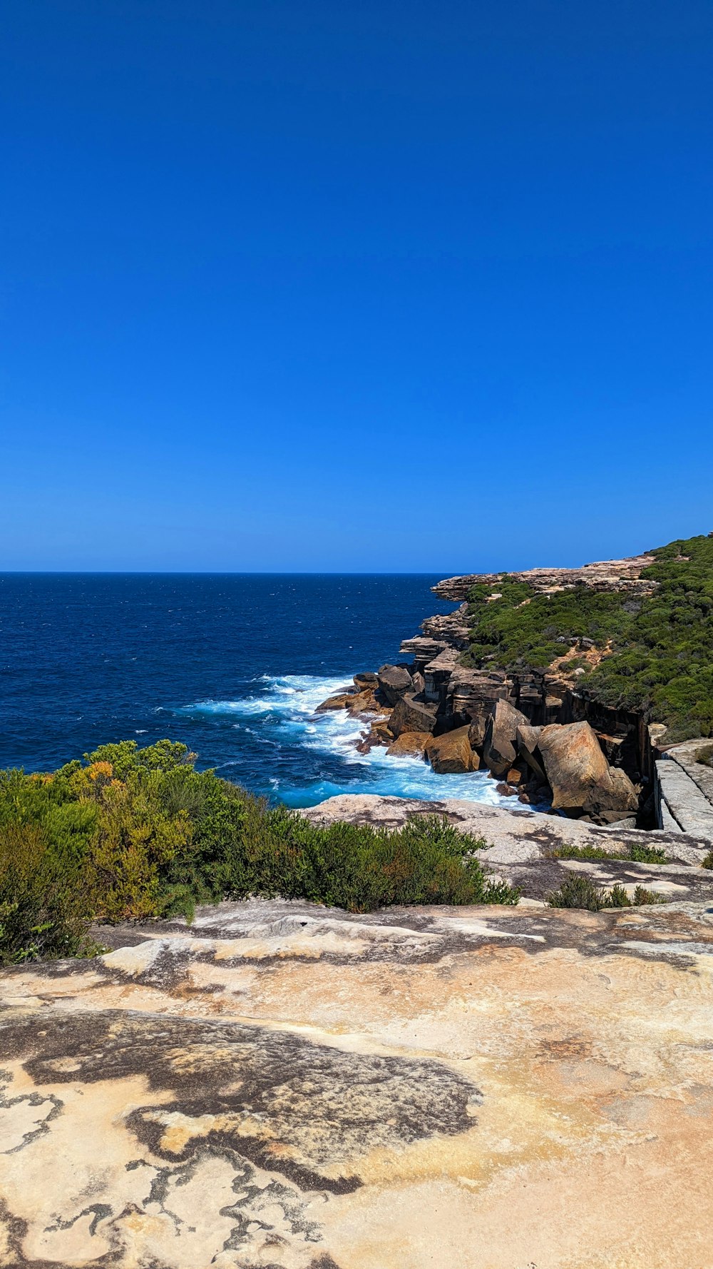 a bench sitting on top of a cliff next to the ocean