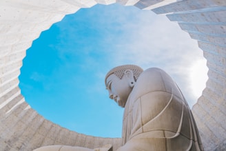 a large buddha statue sitting under a blue sky