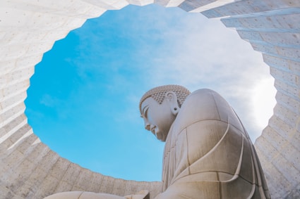 a large buddha statue sitting under a blue sky