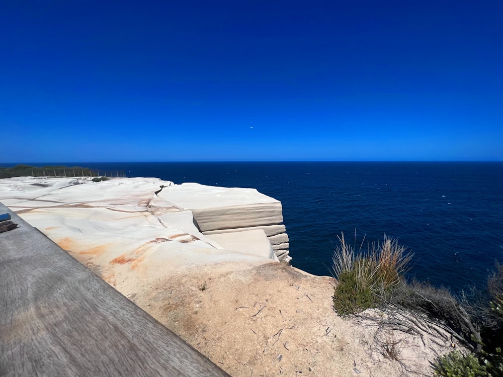 a bench sitting on top of a cliff next to the ocean