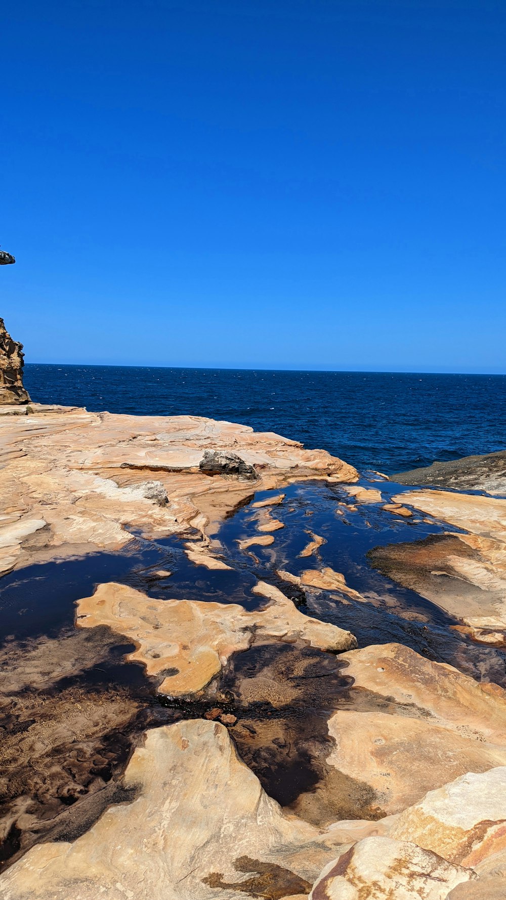 海に面した岩だらけの崖の上に座るベンチ