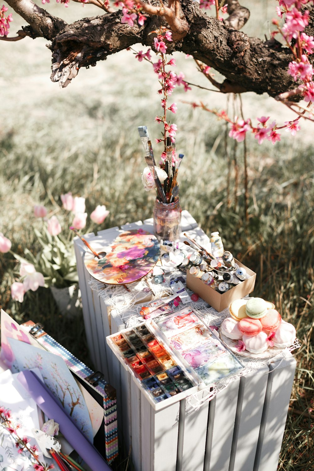 a table covered in art supplies under a tree