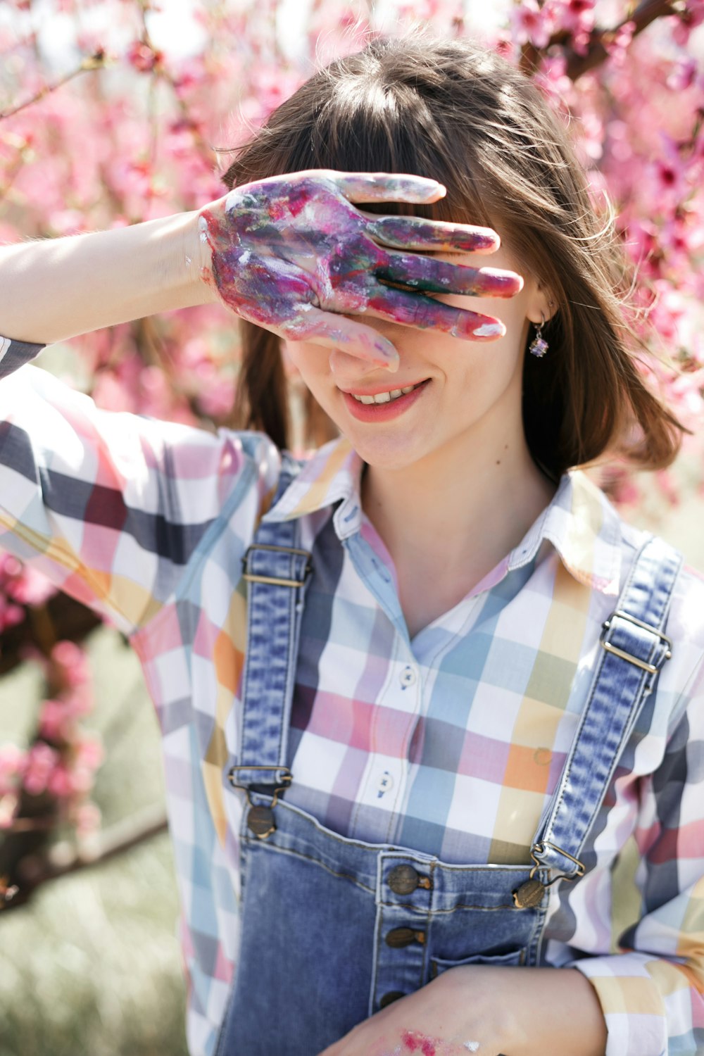 a woman wearing overalls and a checkered shirt is looking through a pair of