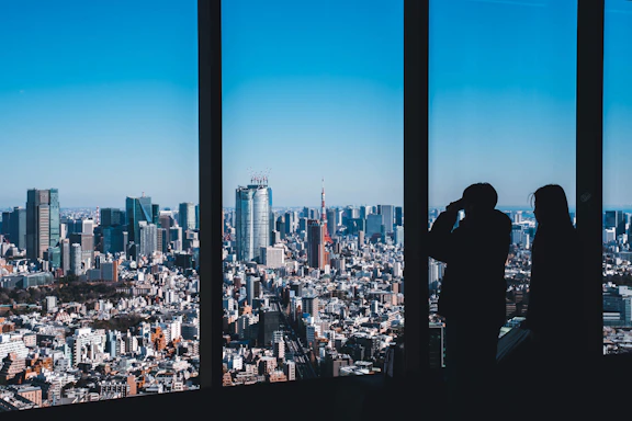 A confident Indian male and female IT professionals standing in front of a sleek Bangalore city skyline with modern high-rise buildings.
