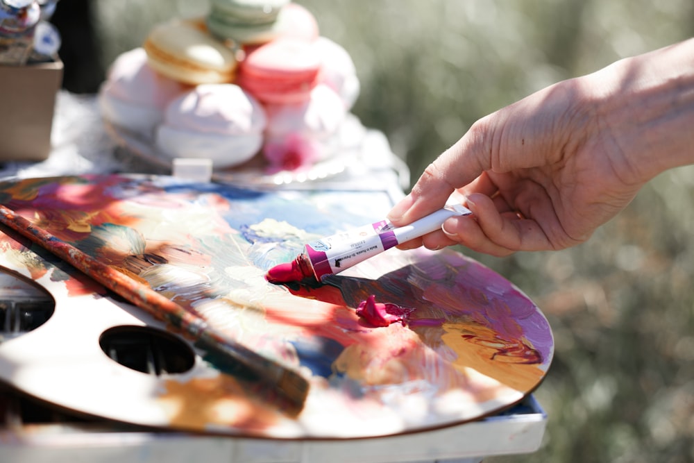 a person holding a paintbrush painting a picture on an easel