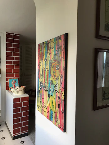 A vibrant traditional painting with rich textures and bold colors displayed on a clean white wall.