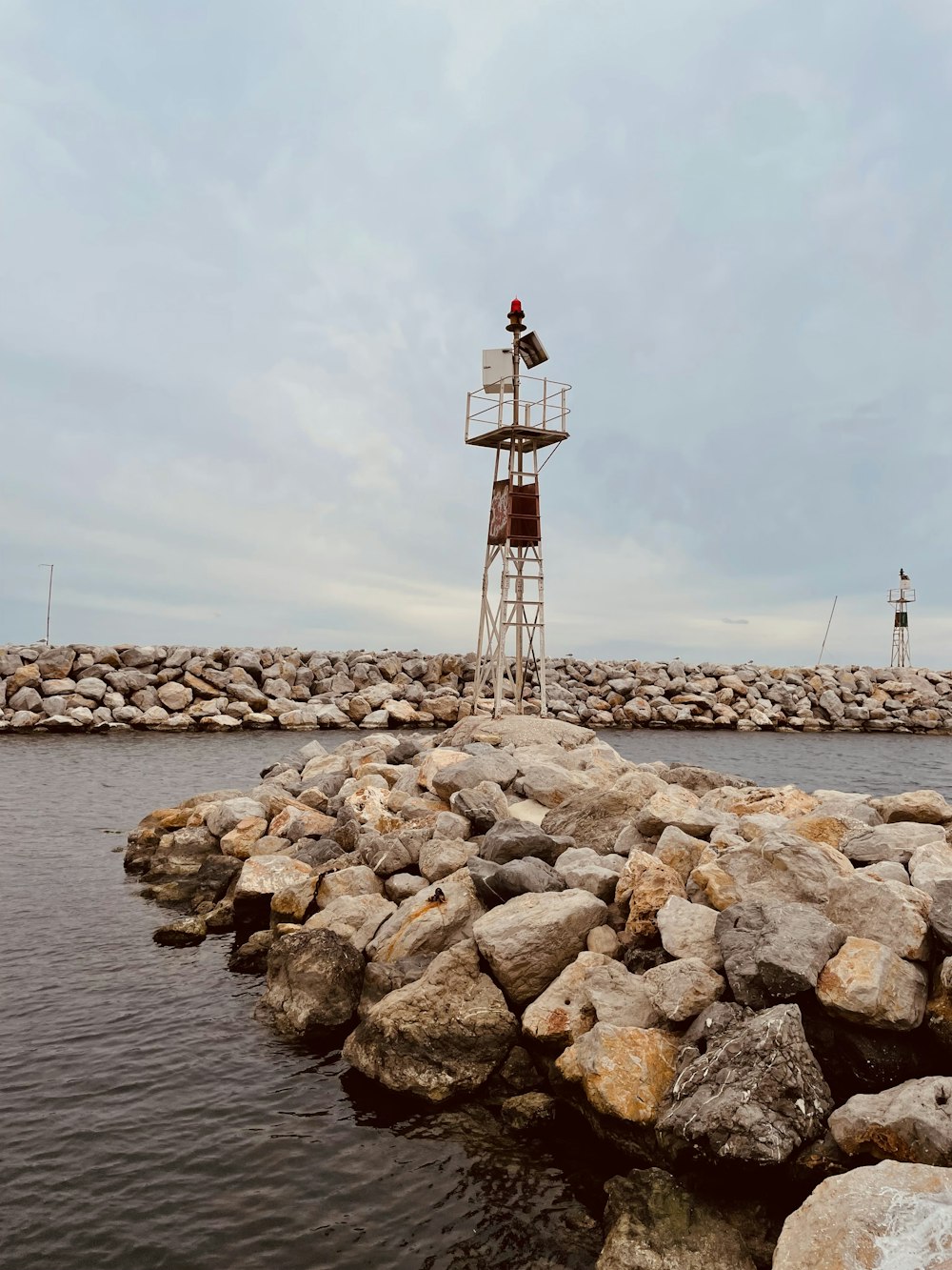 uma torre de salva-vidas sentada no topo de um cais rochoso