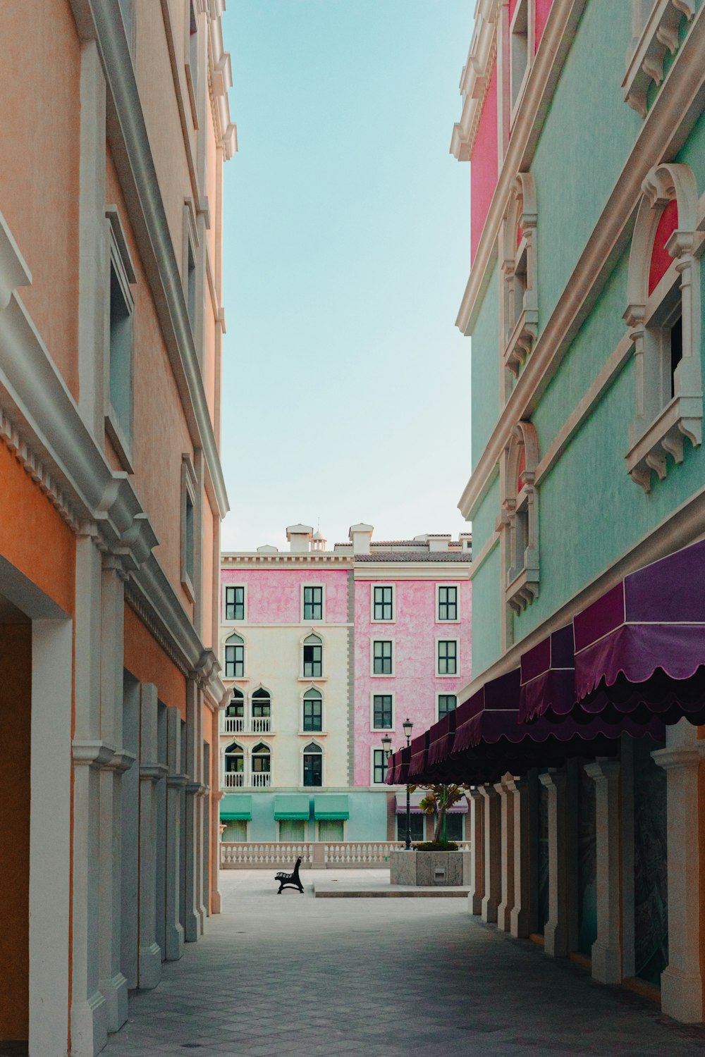 a person sitting on a bench in an alley between two buildings