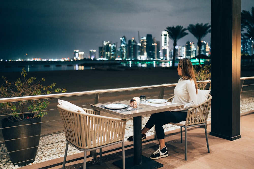 a woman sitting at a table with a view of a city