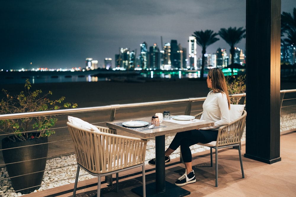 une femme assise à une table avec vue sur une ville