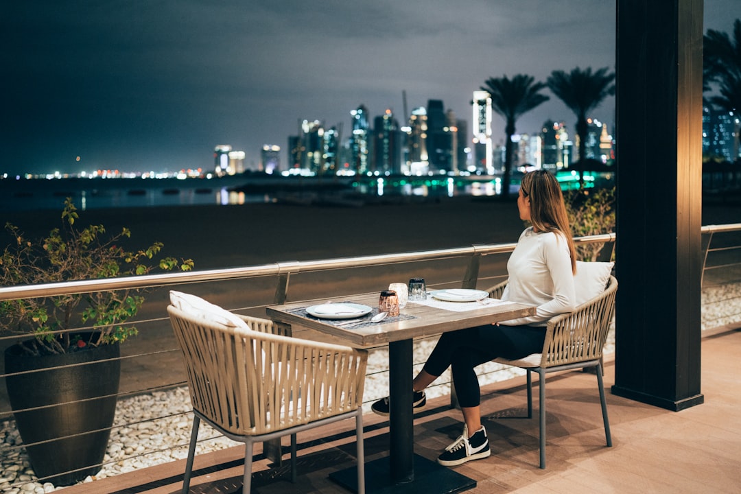a woman sitting at a table with a view of a city,