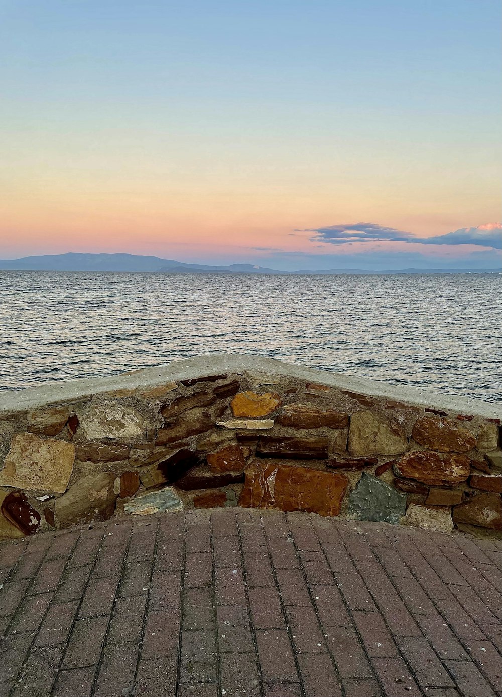 바다 근처의 벽돌 산책로 위에 앉아있는 벤치