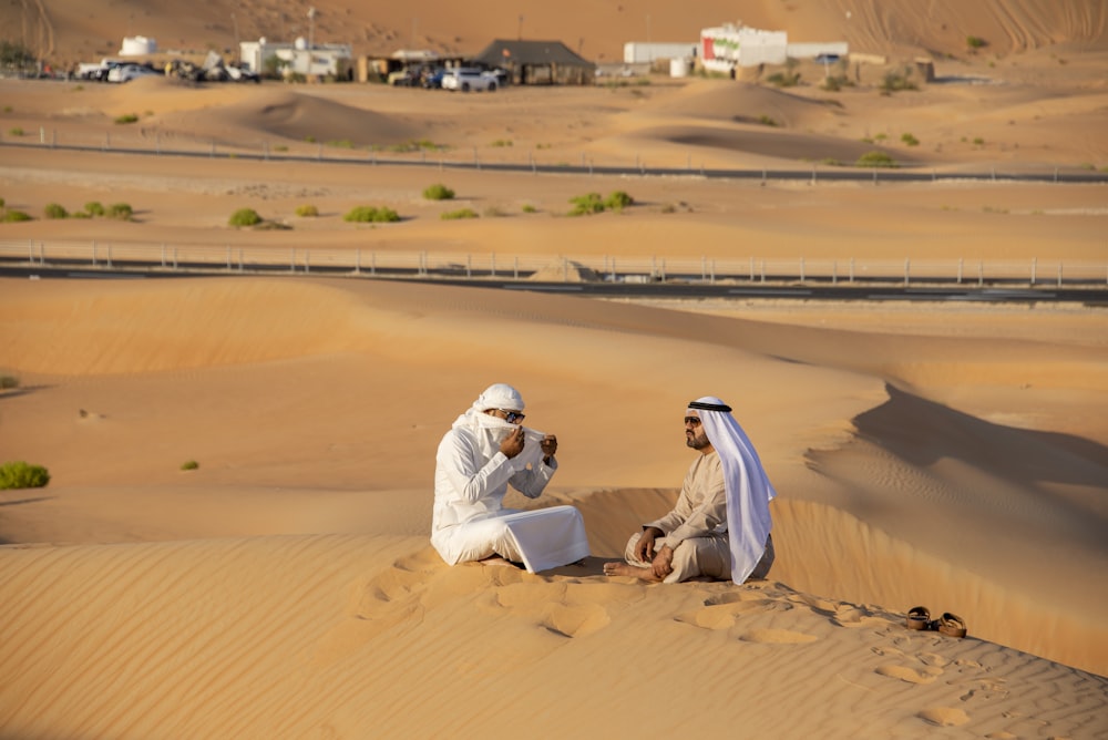 a couple of men sitting on top of a desert