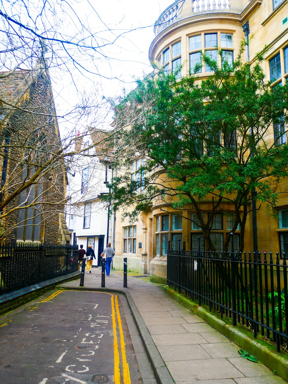 a couple of people walking down a street next to tall buildings