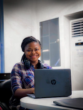 Close-up of a smiling agent typing on a laptop with headset on.