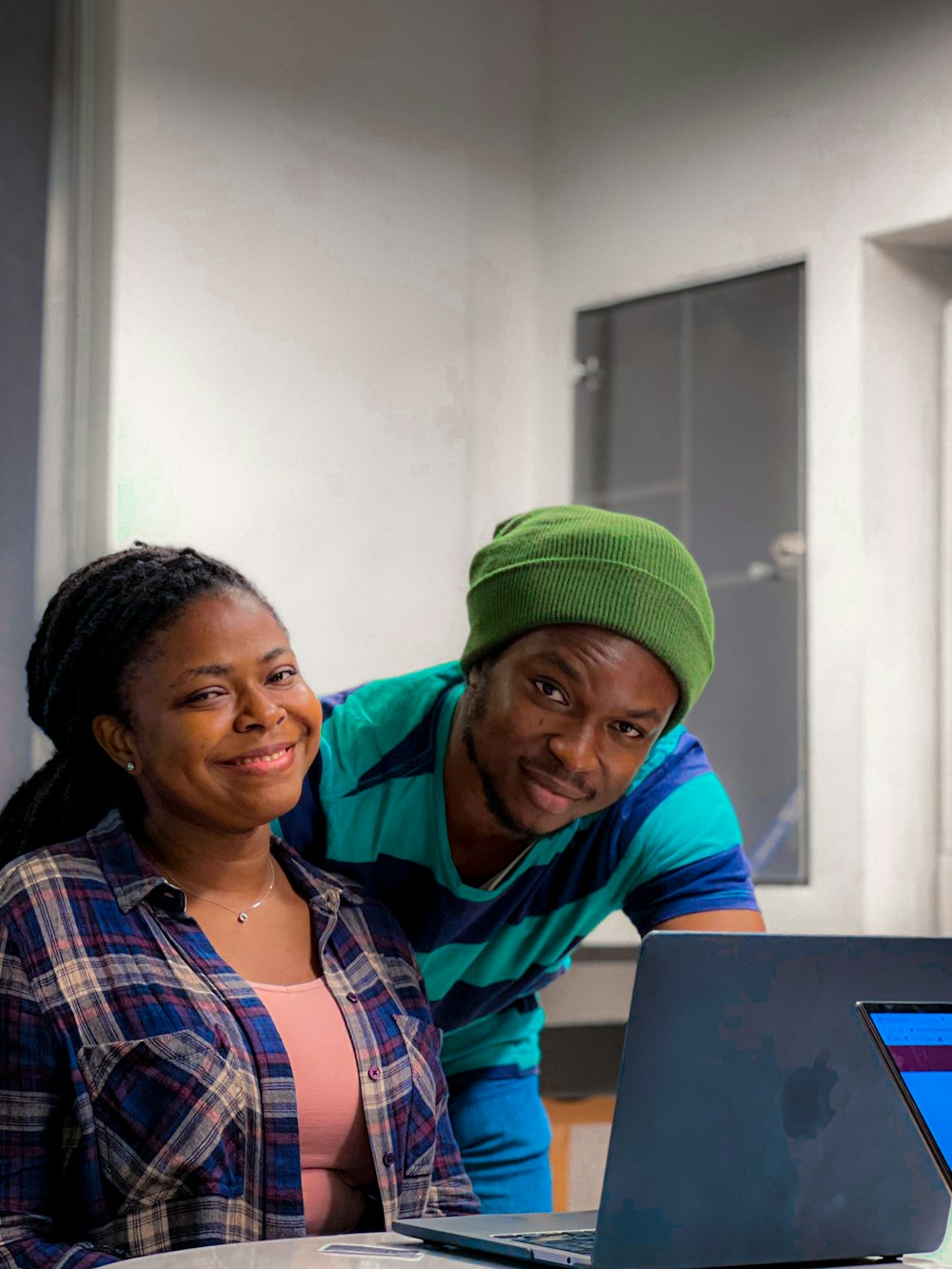 a man and a woman are looking at a laptop