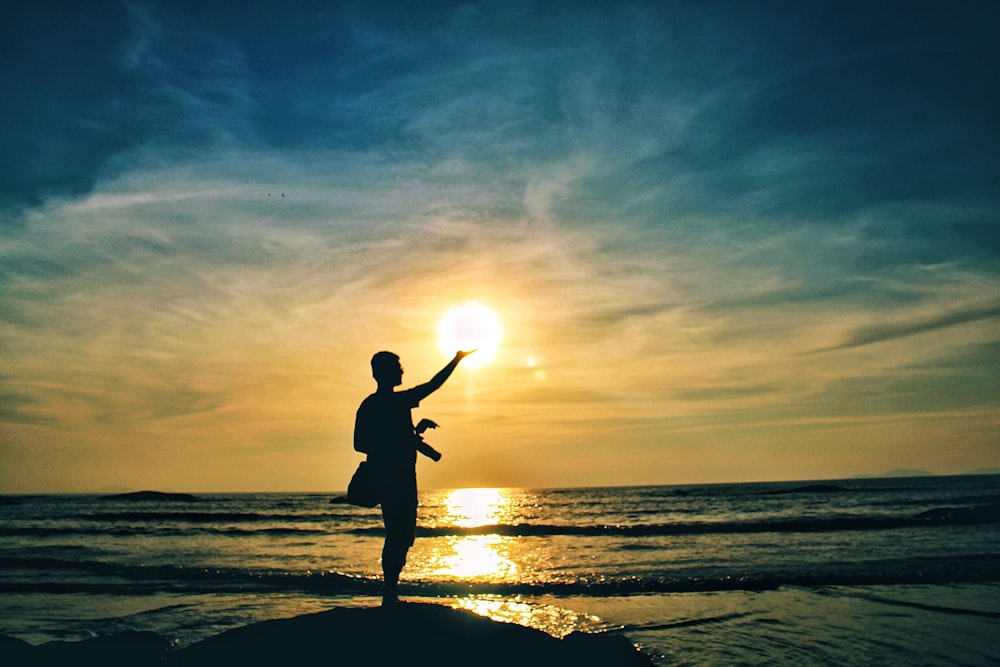 a person standing on a rock at the beach