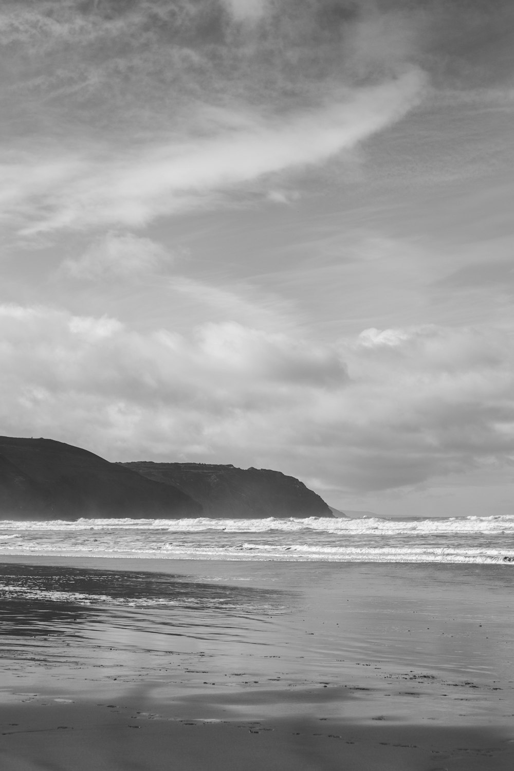 Ein Schwarz-Weiß-Foto einer Person, die am Strand spazieren geht