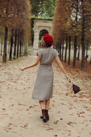 A stylish woman wearing a structured beret walking through a bustling city street in autumn.