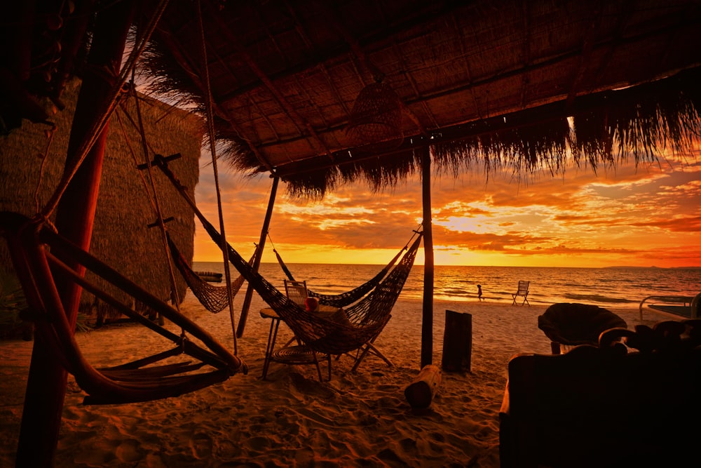 a hammock on the beach with a sunset in the background